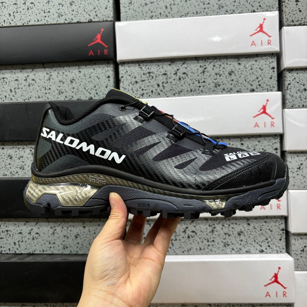 Side profile of the Salomon XT-4 OG trail running sneaker in a sleek all-black colorway, featuring a durable TPU film mesh upper, a Quicklace system, and an aggressive Contagrip rubber outsole.