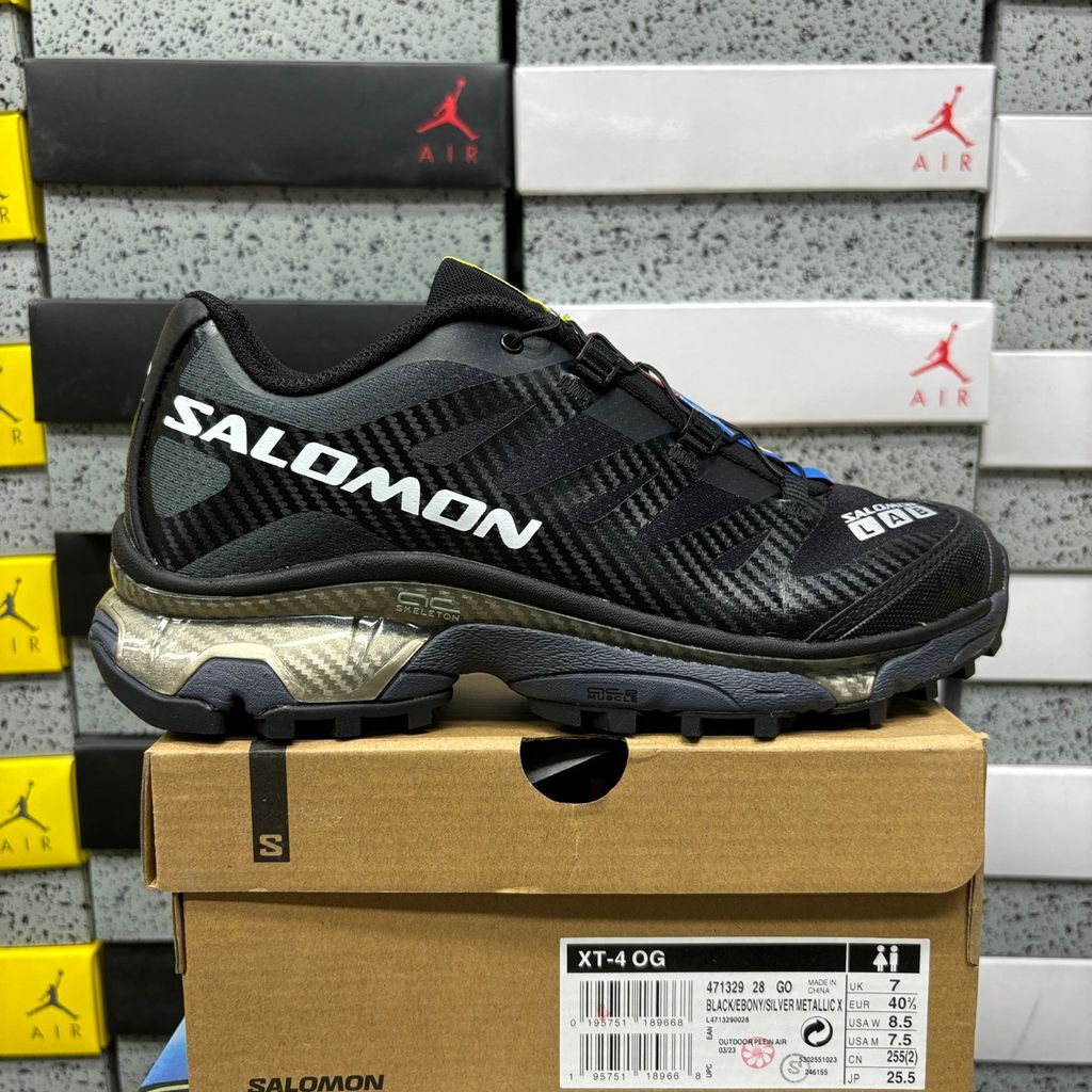 Side profile of the Salomon XT-4 OG trail running sneaker in a sleek all-black colorway, featuring a durable TPU film mesh upper, a Quicklace system, and an aggressive Contagrip rubber outsole.
