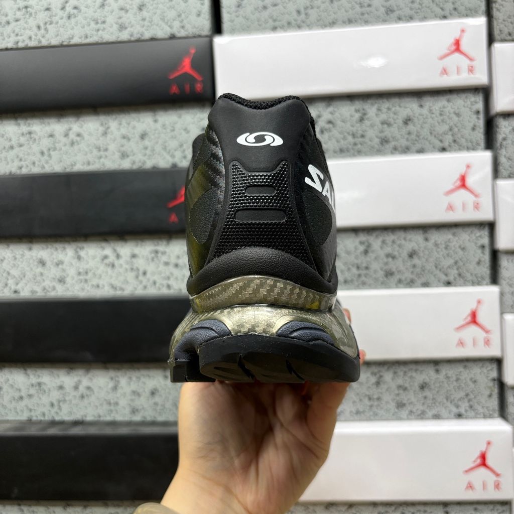 Side profile of the Salomon XT-4 OG trail running sneaker in a sleek all-black colorway, featuring a durable TPU film mesh upper, a Quicklace system, and an aggressive Contagrip rubber outsole.