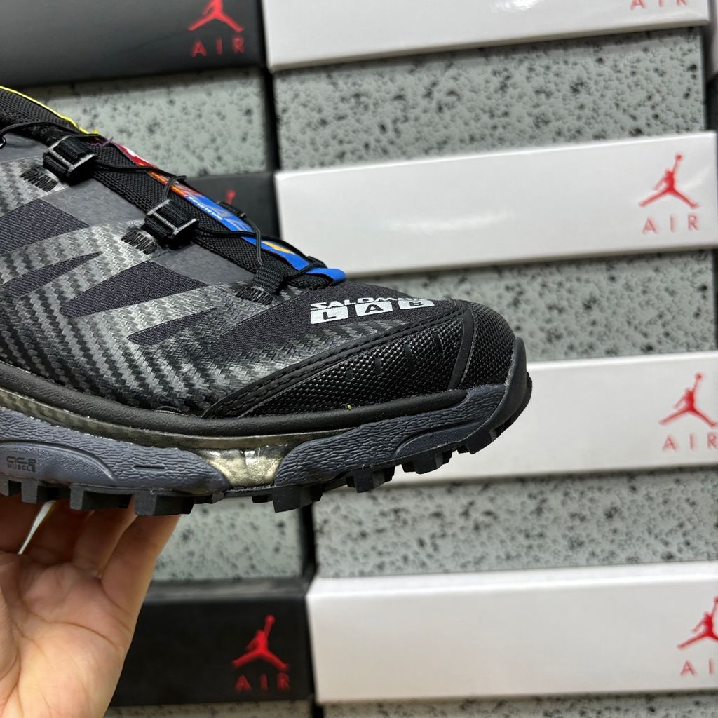 Side profile of the Salomon XT-4 OG trail running sneaker in a sleek all-black colorway, featuring a durable TPU film mesh upper, a Quicklace system, and an aggressive Contagrip rubber outsole.