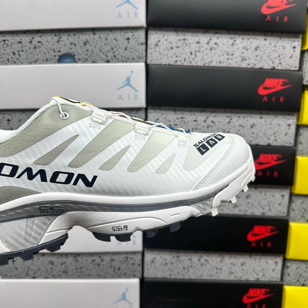 Side profile of the Salomon XT-4 OG trail running sneaker in a clean White and Lunar Rock colorway, featuring a durable TPU film mesh upper, a Quicklace system, and an aggressive Contagrip rubber outsole.