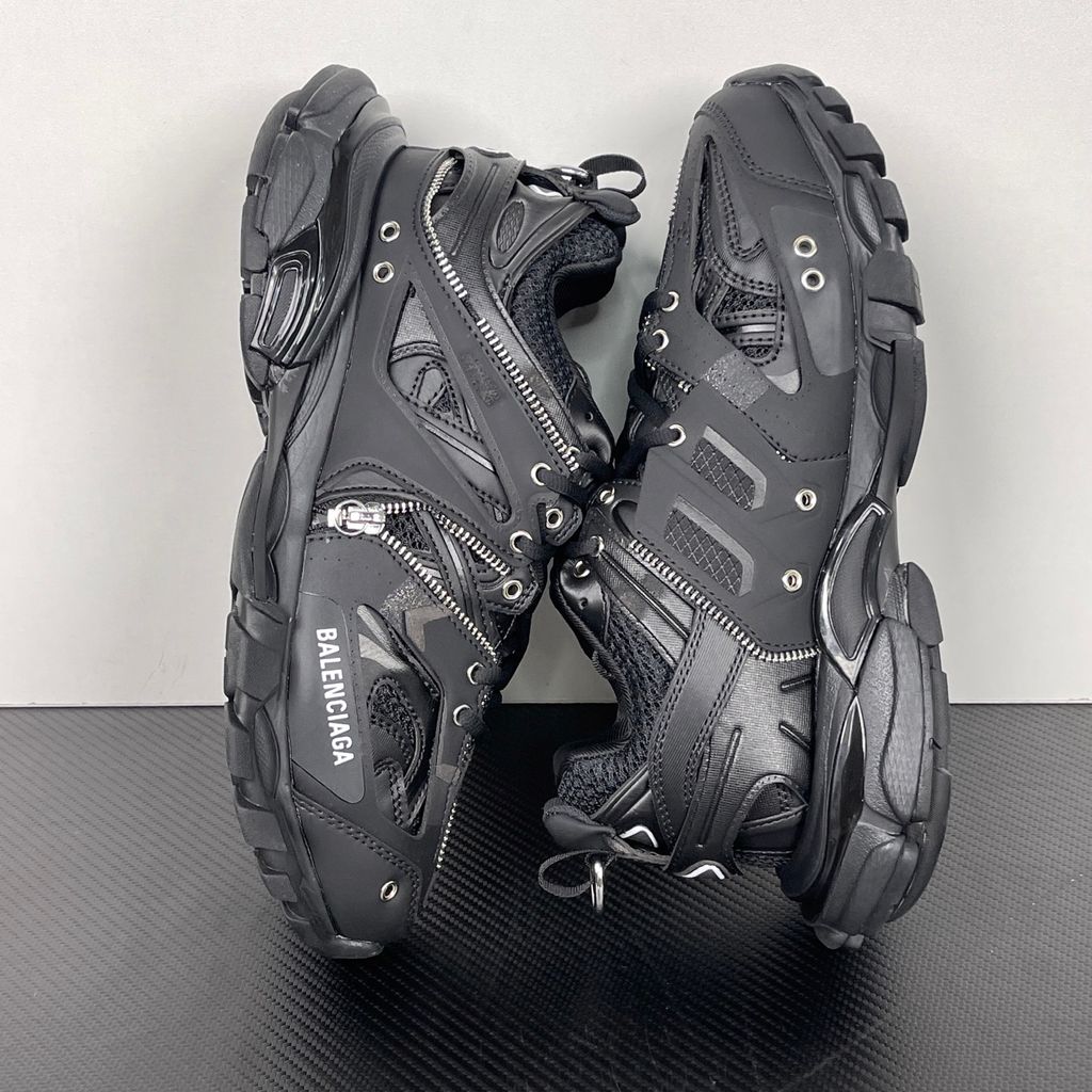 Side profile of the Balenciaga Track LED sneaker in an all-black colorway, featuring a complex layered mesh and synthetic upper, metallic zipper embellishments across the side panels, a chunky augmented sole, and a built-in LED heel display.
