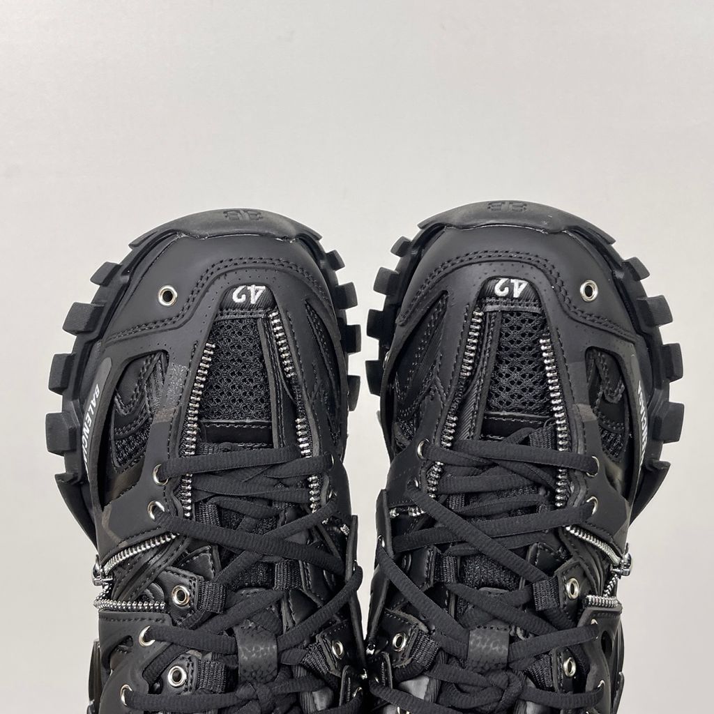 Side profile of the Balenciaga Track LED sneaker in an all-black colorway, featuring a complex layered mesh and synthetic upper, metallic zipper embellishments across the side panels, a chunky augmented sole, and a built-in LED heel display.