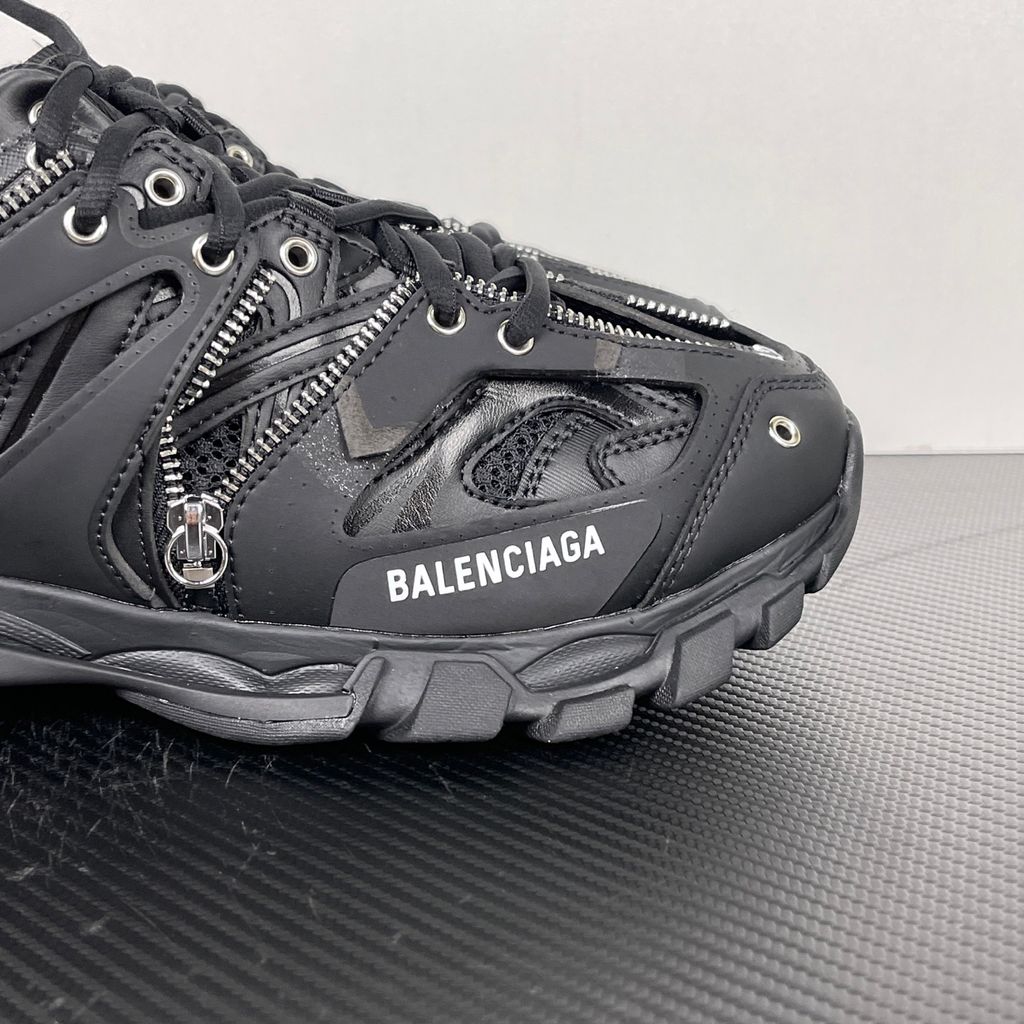 Side profile of the Balenciaga Track LED sneaker in an all-black colorway, featuring a complex layered mesh and synthetic upper, metallic zipper embellishments across the side panels, a chunky augmented sole, and a built-in LED heel display.