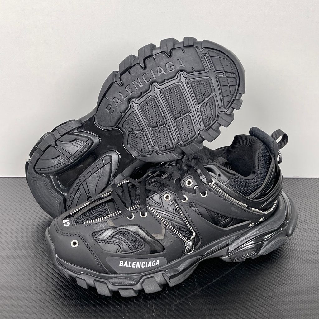 Side profile of the Balenciaga Track LED sneaker in an all-black colorway, featuring a complex layered mesh and synthetic upper, metallic zipper embellishments across the side panels, a chunky augmented sole, and a built-in LED heel display.