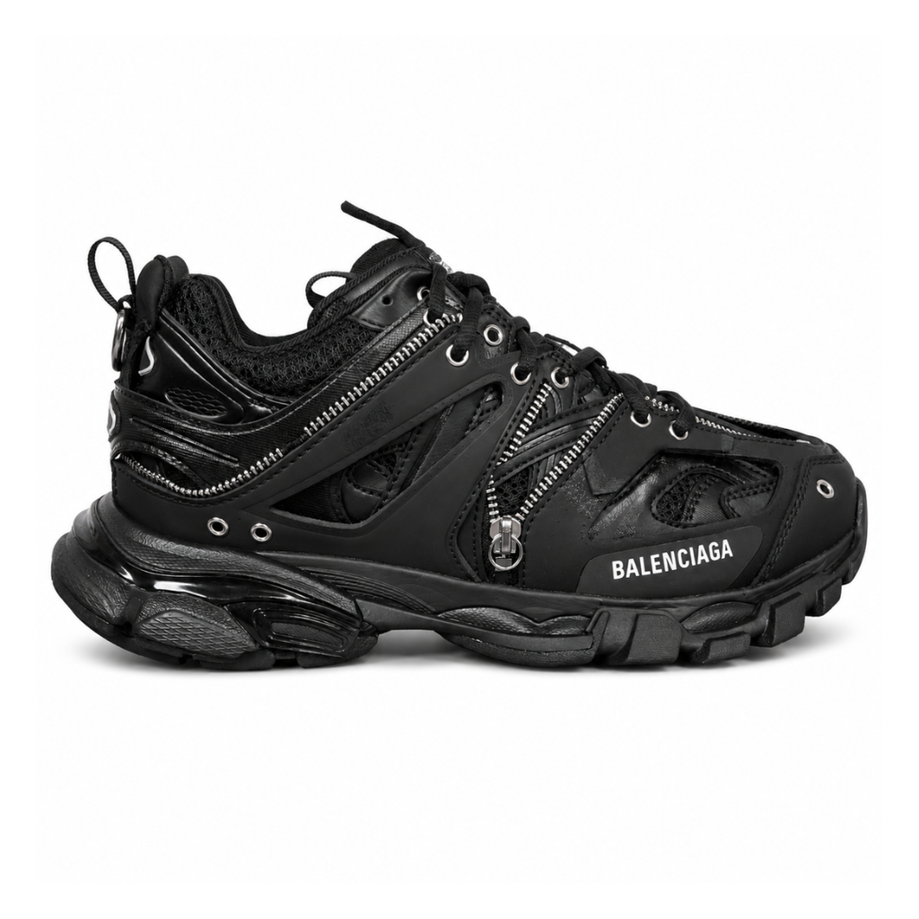 Side profile of the Balenciaga Track LED sneaker in an all-black colorway, featuring a complex layered mesh and synthetic upper, metallic zipper embellishments across the side panels, a chunky augmented sole, and a built-in LED heel display.