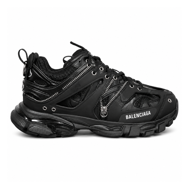 Side profile of the Balenciaga Track LED sneaker in an all-black colorway, featuring a complex layered mesh and synthetic upper, metallic zipper embellishments across the side panels, a chunky augmented sole, and a built-in LED heel display.