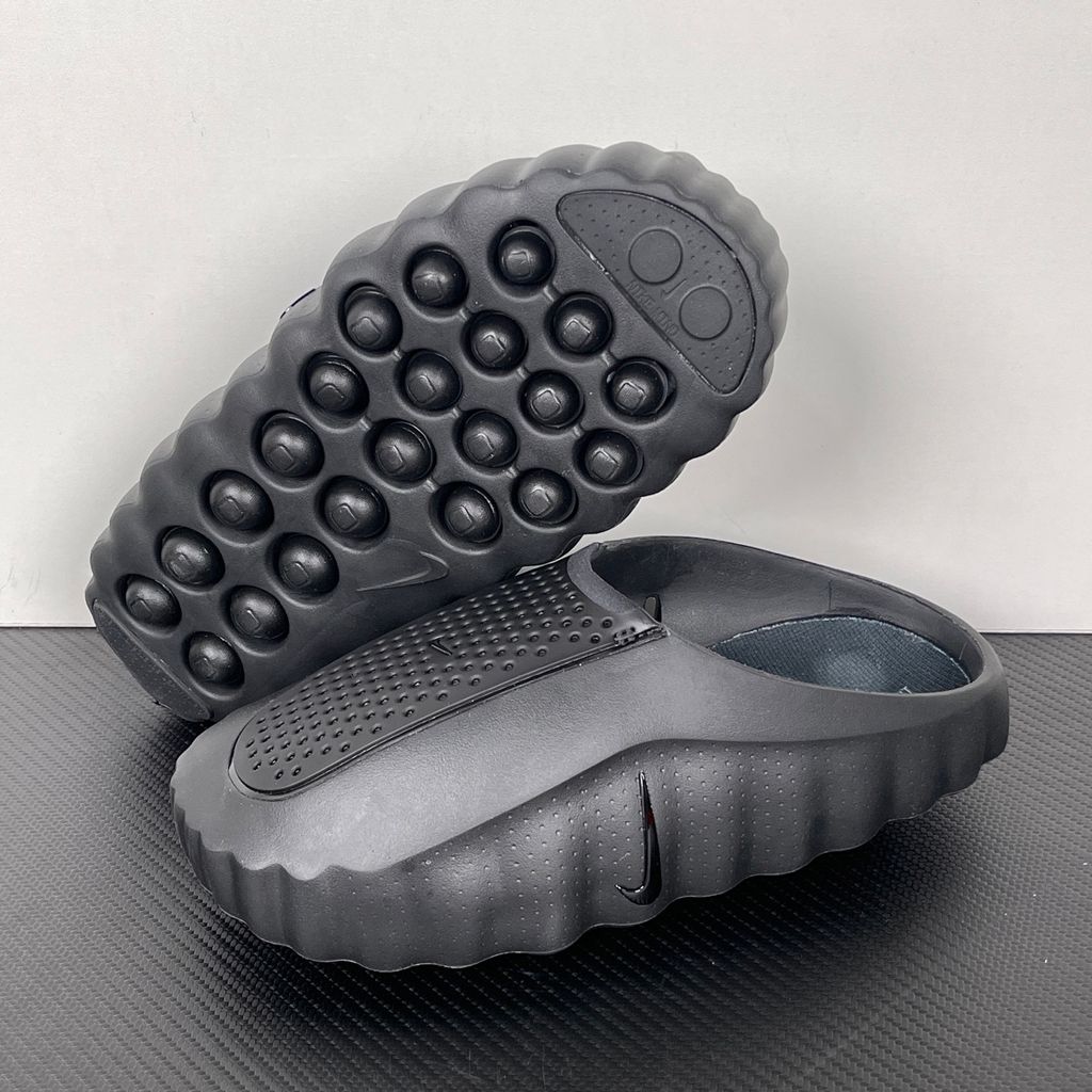 Side profile of the Nike Mind 001 Slide in a sleek Triple Black colorway, featuring a seamless, minimalist foam construction, a contoured footbed, and a durable traction outsole.