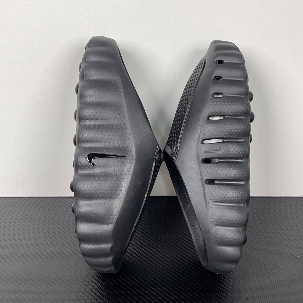 Side profile of the Nike Mind 001 Slide in a sleek Triple Black colorway, featuring a seamless, minimalist foam construction, a contoured footbed, and a durable traction outsole.
