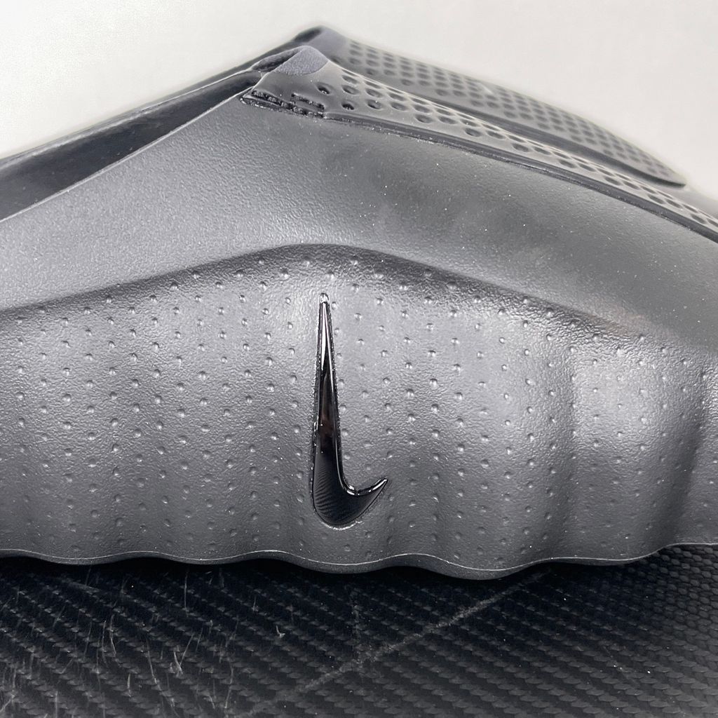 Side profile of the Nike Mind 001 Slide in a sleek Triple Black colorway, featuring a seamless, minimalist foam construction, a contoured footbed, and a durable traction outsole.