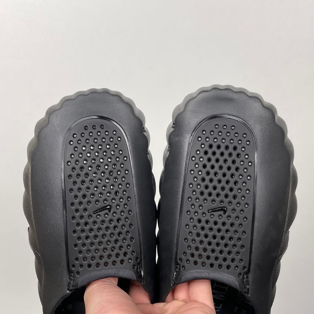 Side profile of the Nike Mind 001 Slide in a sleek Triple Black colorway, featuring a seamless, minimalist foam construction, a contoured footbed, and a durable traction outsole.