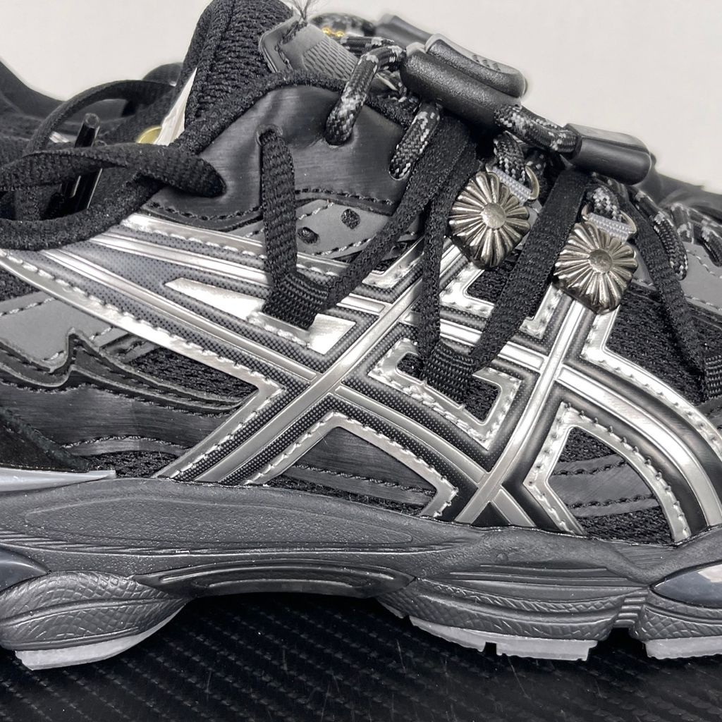 Side profile of the collaborative ASICS x TOGA Gel-Cumulus 16 sneaker in a Grey, Black, and Pure Silver colorway, featuring a breathable mesh upper, striking metallic silver overlays, sleek black accents, and a sculpted GEL-cushioned midsole.