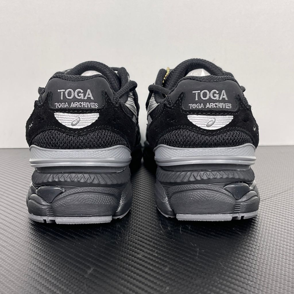 Side profile of the collaborative ASICS x TOGA Gel-Cumulus 16 sneaker in a Grey, Black, and Pure Silver colorway, featuring a breathable mesh upper, striking metallic silver overlays, sleek black accents, and a sculpted GEL-cushioned midsole.