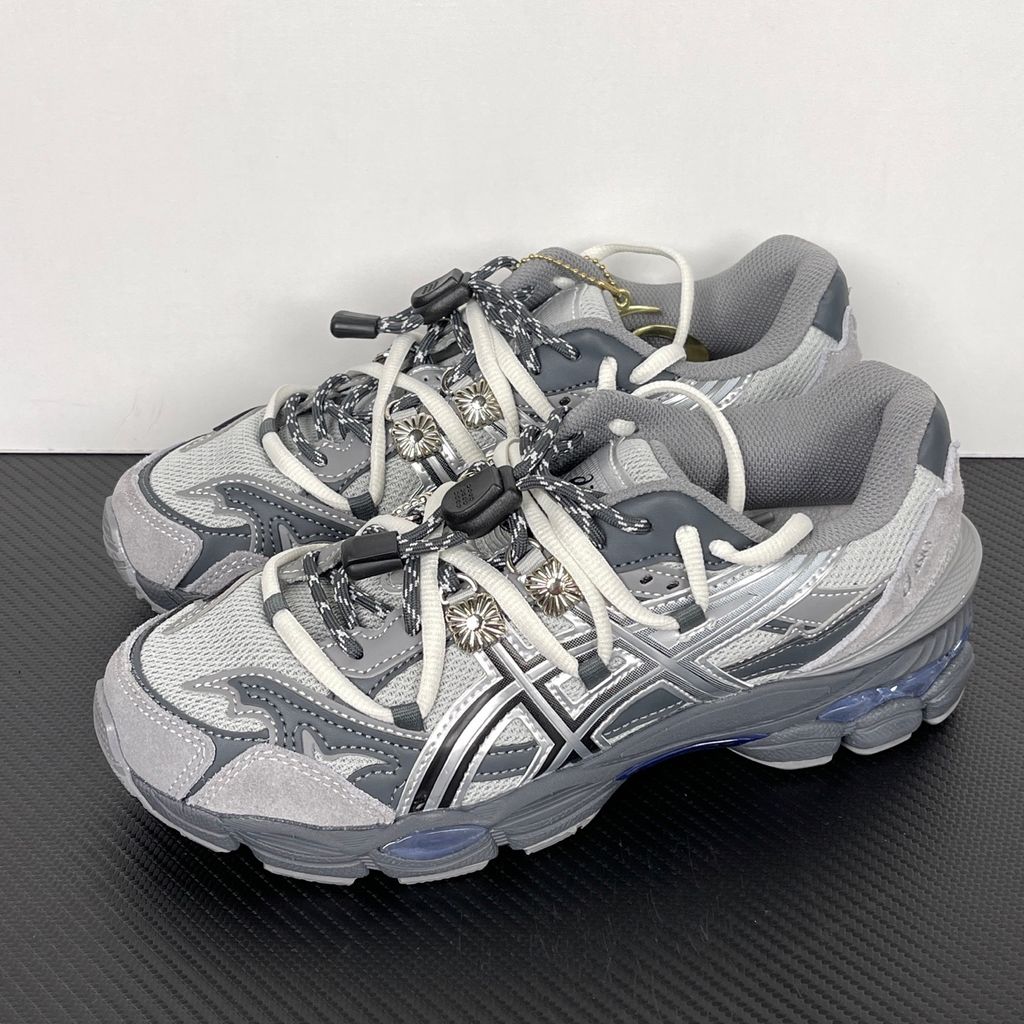 Side profile of the collaborative ASICS x TOGA Gel-Cumulus 16 sneaker in a Grey, Black, and Pure Silver colorway, featuring a breathable mesh upper, striking metallic silver overlays, sleek black accents, and a sculpted GEL-cushioned midsole.