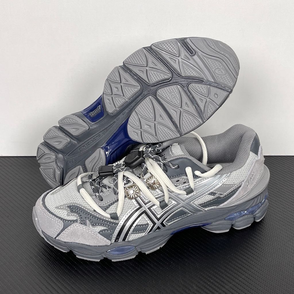 Side profile of the collaborative ASICS x TOGA Gel-Cumulus 16 sneaker in a Grey, Black, and Pure Silver colorway, featuring a breathable mesh upper, striking metallic silver overlays, sleek black accents, and a sculpted GEL-cushioned midsole.