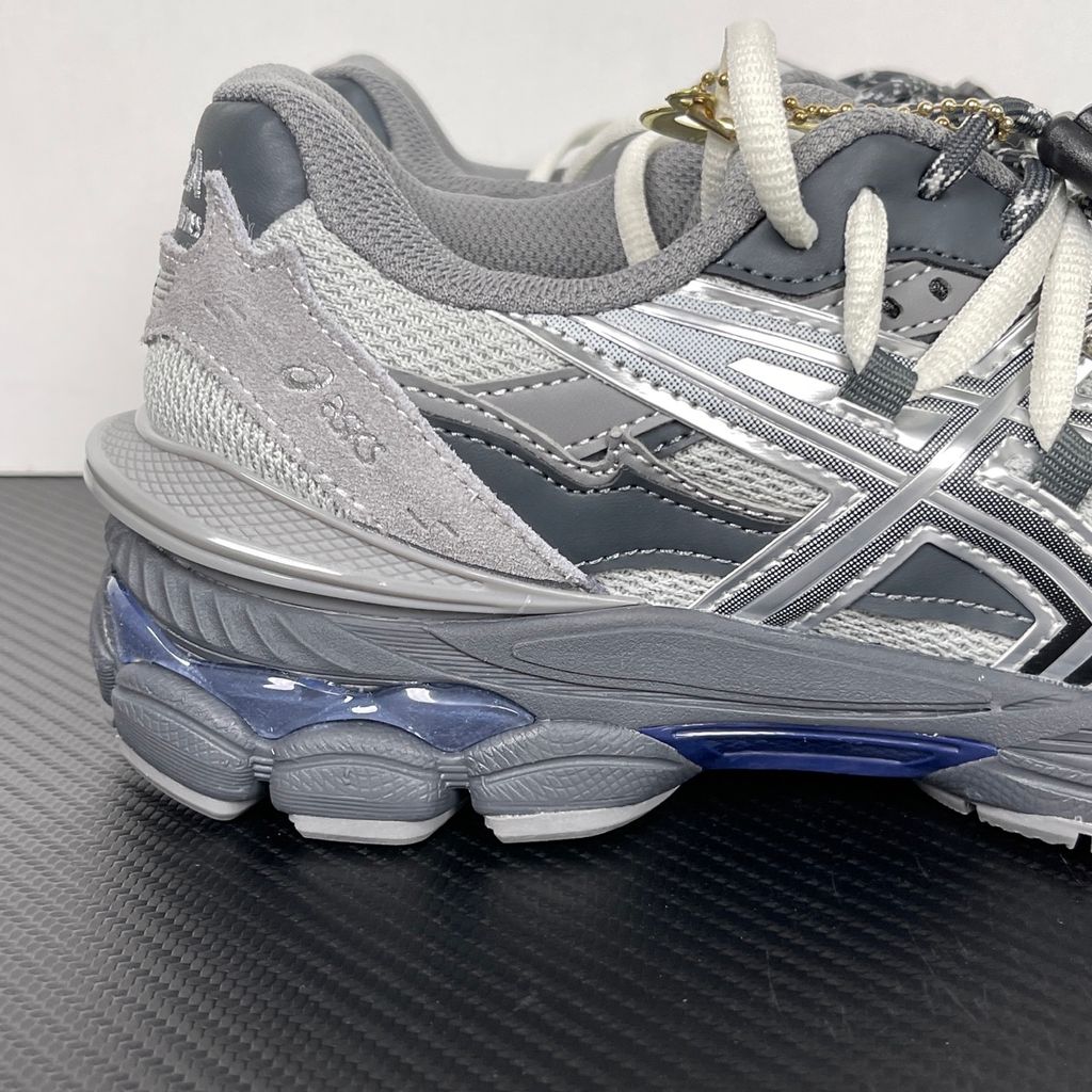 Side profile of the collaborative ASICS x TOGA Gel-Cumulus 16 sneaker in a Grey, Black, and Pure Silver colorway, featuring a breathable mesh upper, striking metallic silver overlays, sleek black accents, and a sculpted GEL-cushioned midsole.