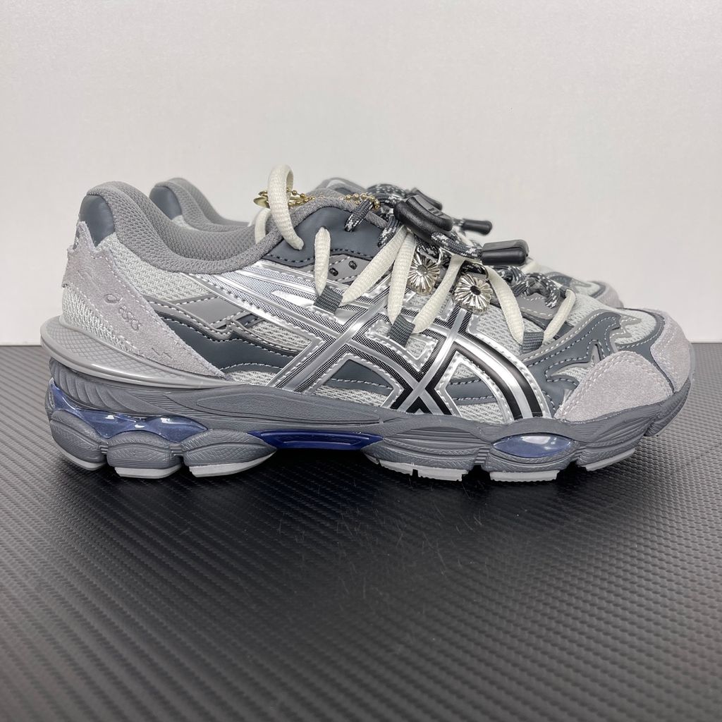 Side profile of the collaborative ASICS x TOGA Gel-Cumulus 16 sneaker in a Grey, Black, and Pure Silver colorway, featuring a breathable mesh upper, striking metallic silver overlays, sleek black accents, and a sculpted GEL-cushioned midsole.