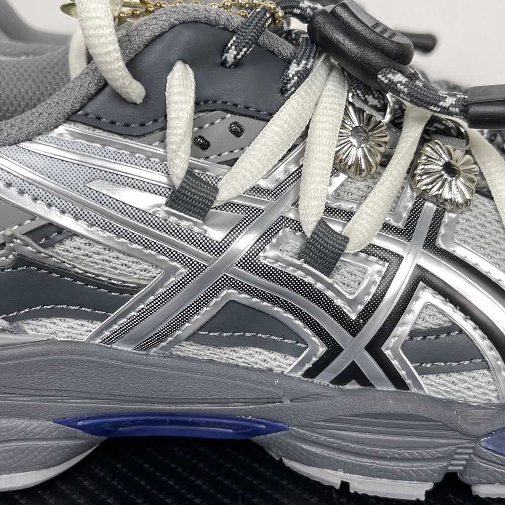 Side profile of the collaborative ASICS x TOGA Gel-Cumulus 16 sneaker in a Grey, Black, and Pure Silver colorway, featuring a breathable mesh upper, striking metallic silver overlays, sleek black accents, and a sculpted GEL-cushioned midsole.