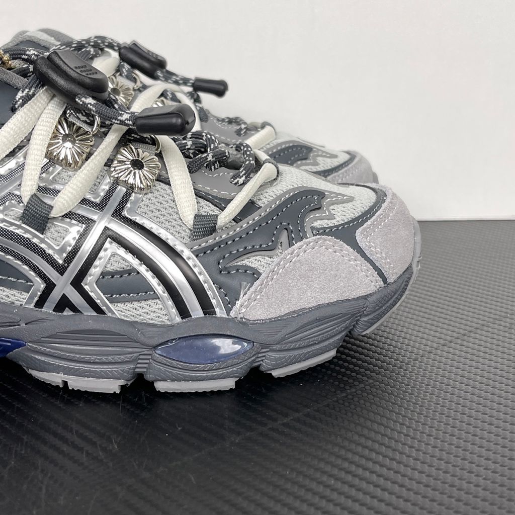 Side profile of the collaborative ASICS x TOGA Gel-Cumulus 16 sneaker in a Grey, Black, and Pure Silver colorway, featuring a breathable mesh upper, striking metallic silver overlays, sleek black accents, and a sculpted GEL-cushioned midsole.