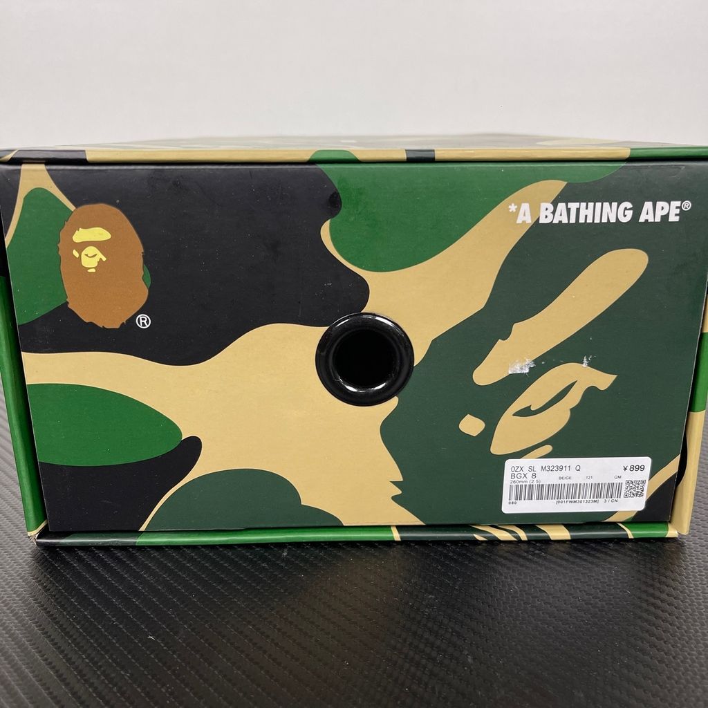 Side profile of the beige A Bathing Ape (BAPE) foam slide (image_889658.jpg), featuring a chunky molded silhouette, a smooth slip-on upper, and deeply debossed signature ape camo patterns wrapping around the midsole and foot strap.