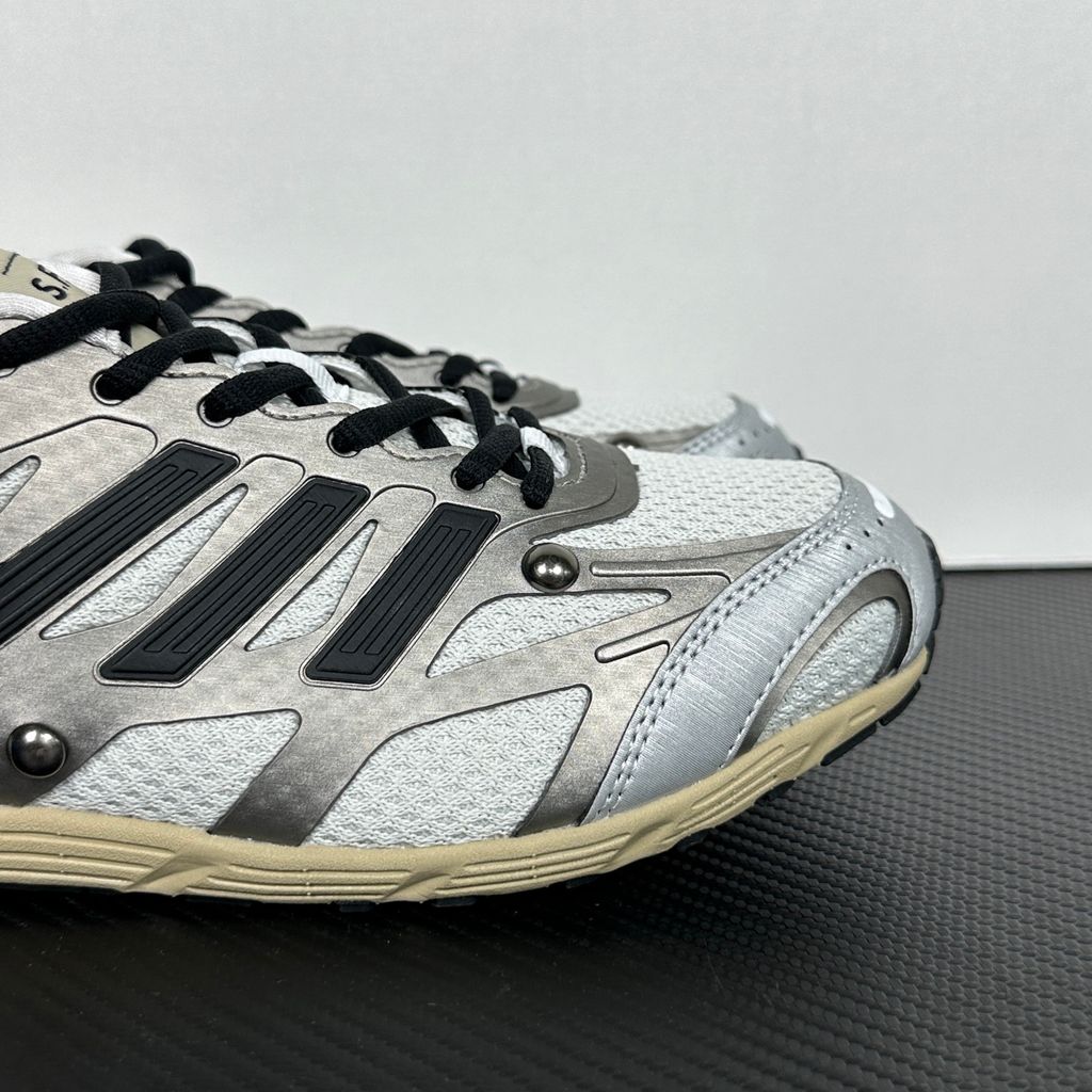 Side profile of the adidas Adizero PR x Song for the Mute collaborative sneaker featuring a crisp white breathable mesh base, gleaming silver metallic synthetic overlays, signature raw-edge and frayed textile accents, and a lightweight cushioned midsole.