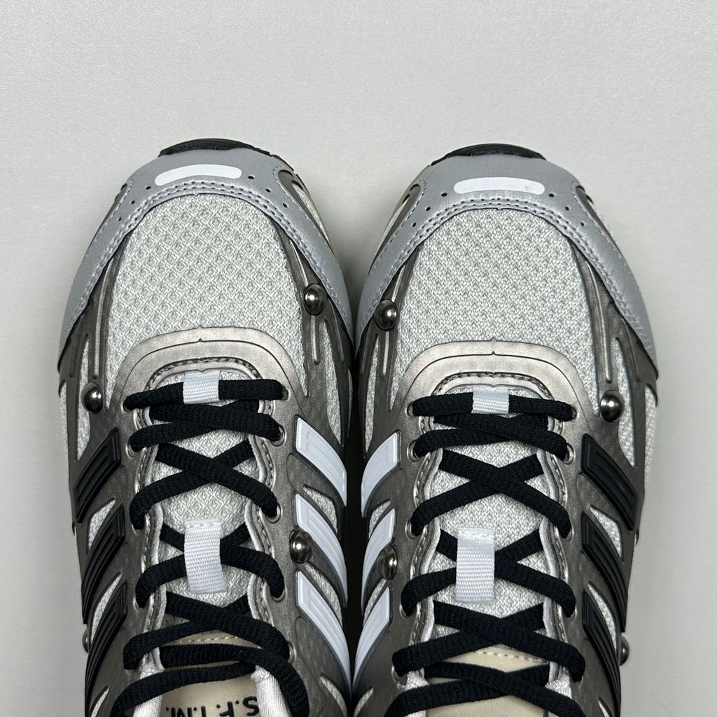 Side profile of the adidas Adizero PR x Song for the Mute collaborative sneaker featuring a crisp white breathable mesh base, gleaming silver metallic synthetic overlays, signature raw-edge and frayed textile accents, and a lightweight cushioned midsole.