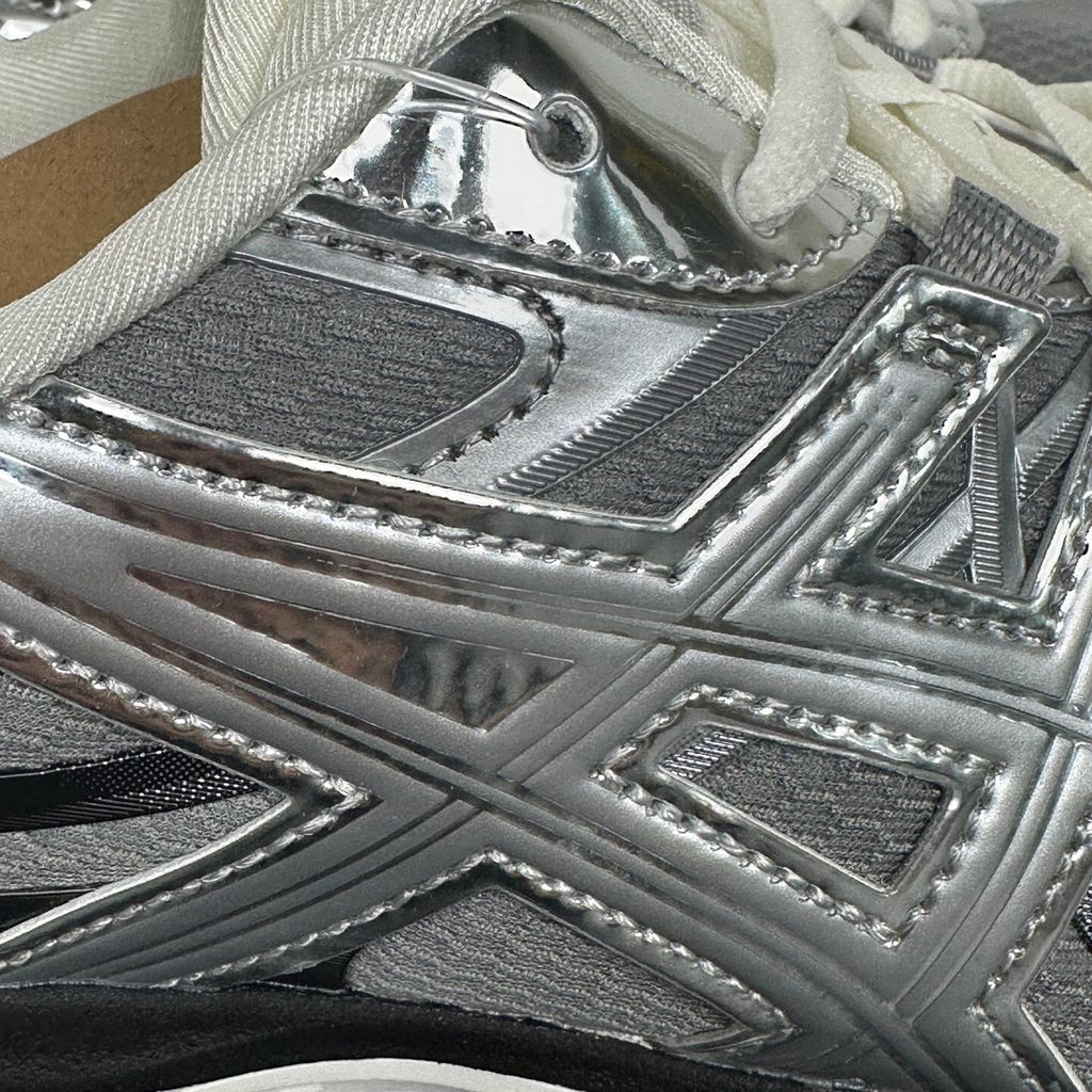 Side profile of the ASICS Gel-Sekiran sneaker featuring a breathable gravel grey mesh upper, dynamic metallic pure silver synthetic overlays, and a sculpted midsole equipped with visible GEL technology cushioning.