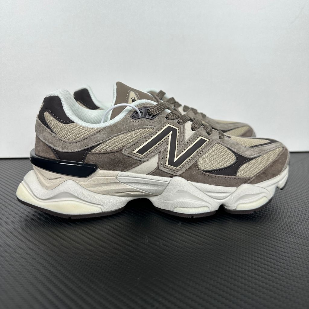 Side profile of the New Balance 9060 sneaker featuring a breathable thunder grey mesh base, rich brown premium suede and nubuck overlays, stonewear accents, the classic 'N' logo, and an exaggerated, sculpted chunky midsole.