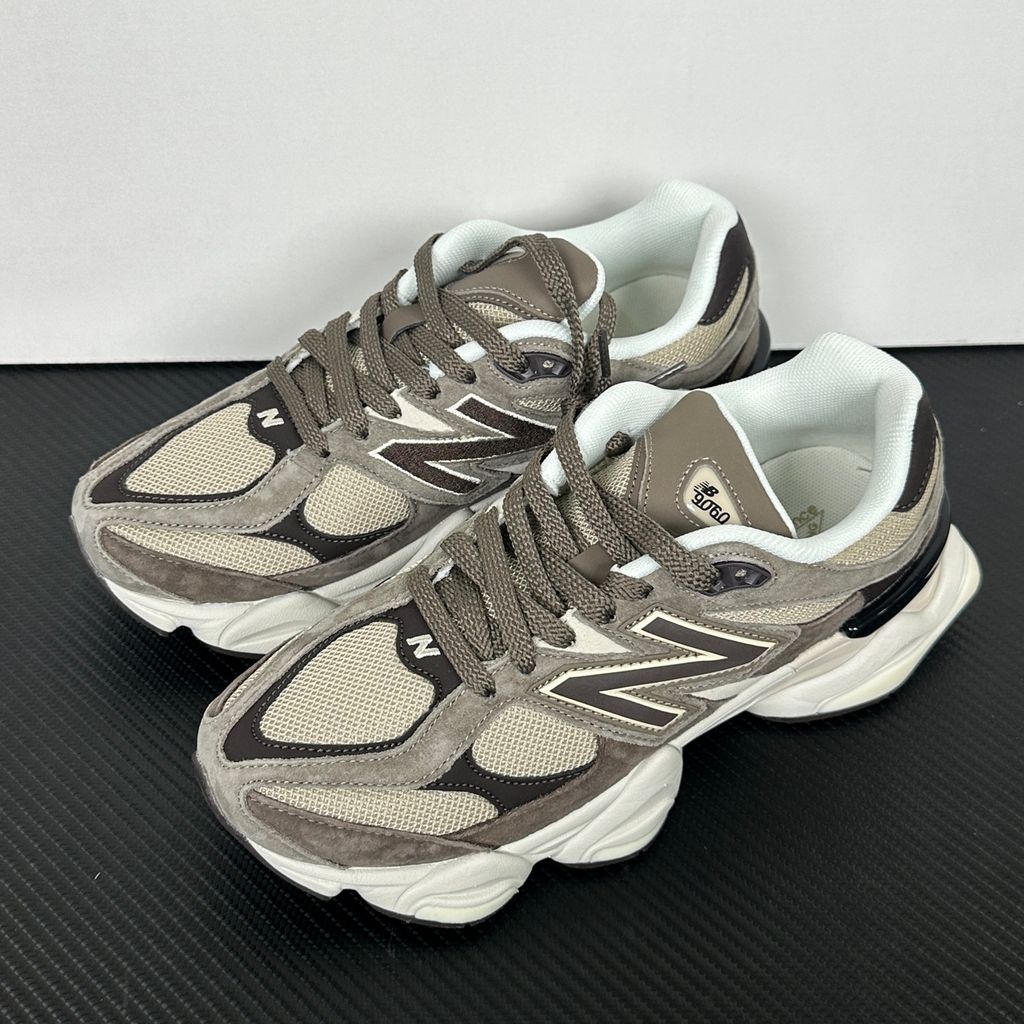 Side profile of the New Balance 9060 sneaker featuring a breathable thunder grey mesh base, rich brown premium suede and nubuck overlays, stonewear accents, the classic 'N' logo, and an exaggerated, sculpted chunky midsole.