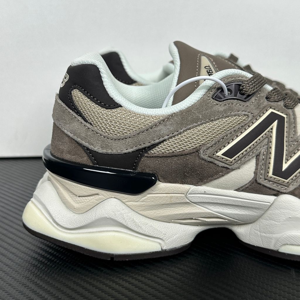 Side profile of the New Balance 9060 sneaker featuring a breathable thunder grey mesh base, rich brown premium suede and nubuck overlays, stonewear accents, the classic 'N' logo, and an exaggerated, sculpted chunky midsole.