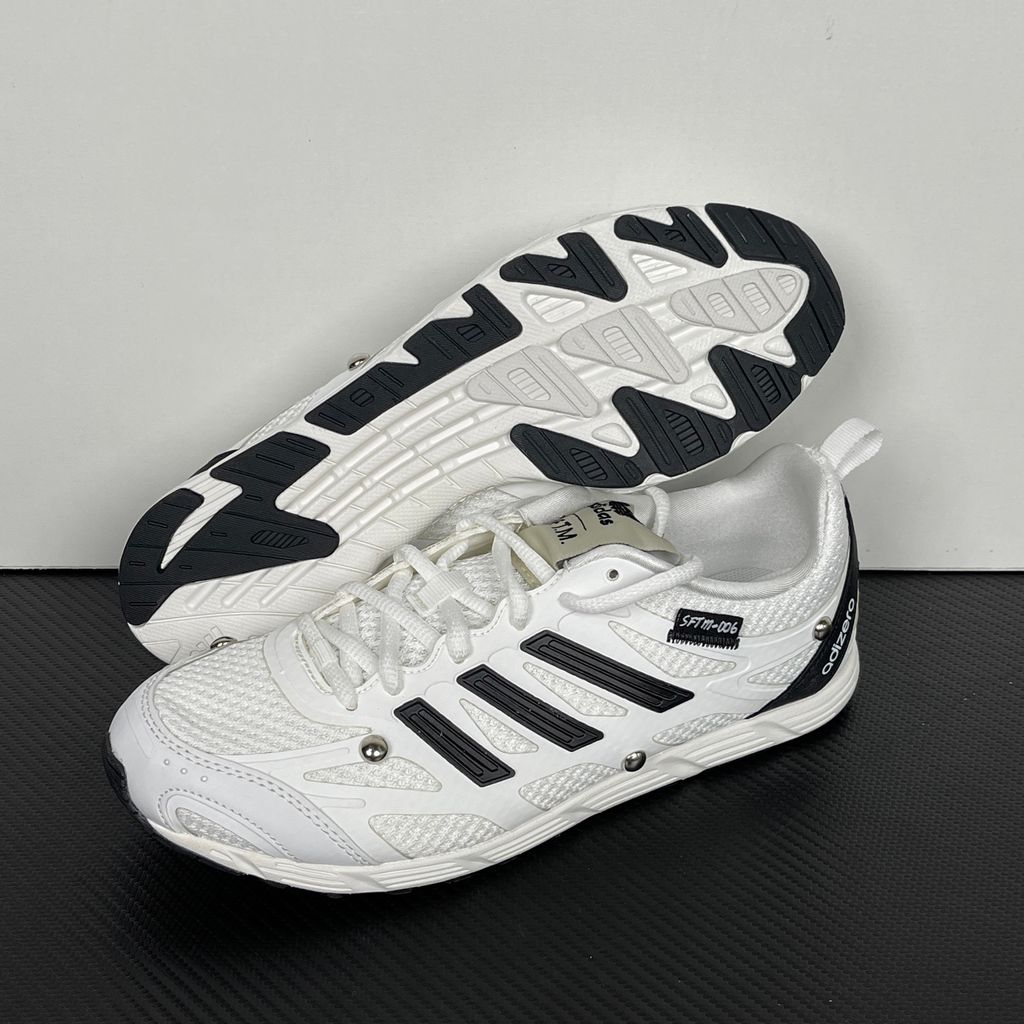 Alt text: Side profile of adidas Adizero PR x Song for the Mute HP3524 in white and black with mesh panels, Three Stripes and silver-tone studs.