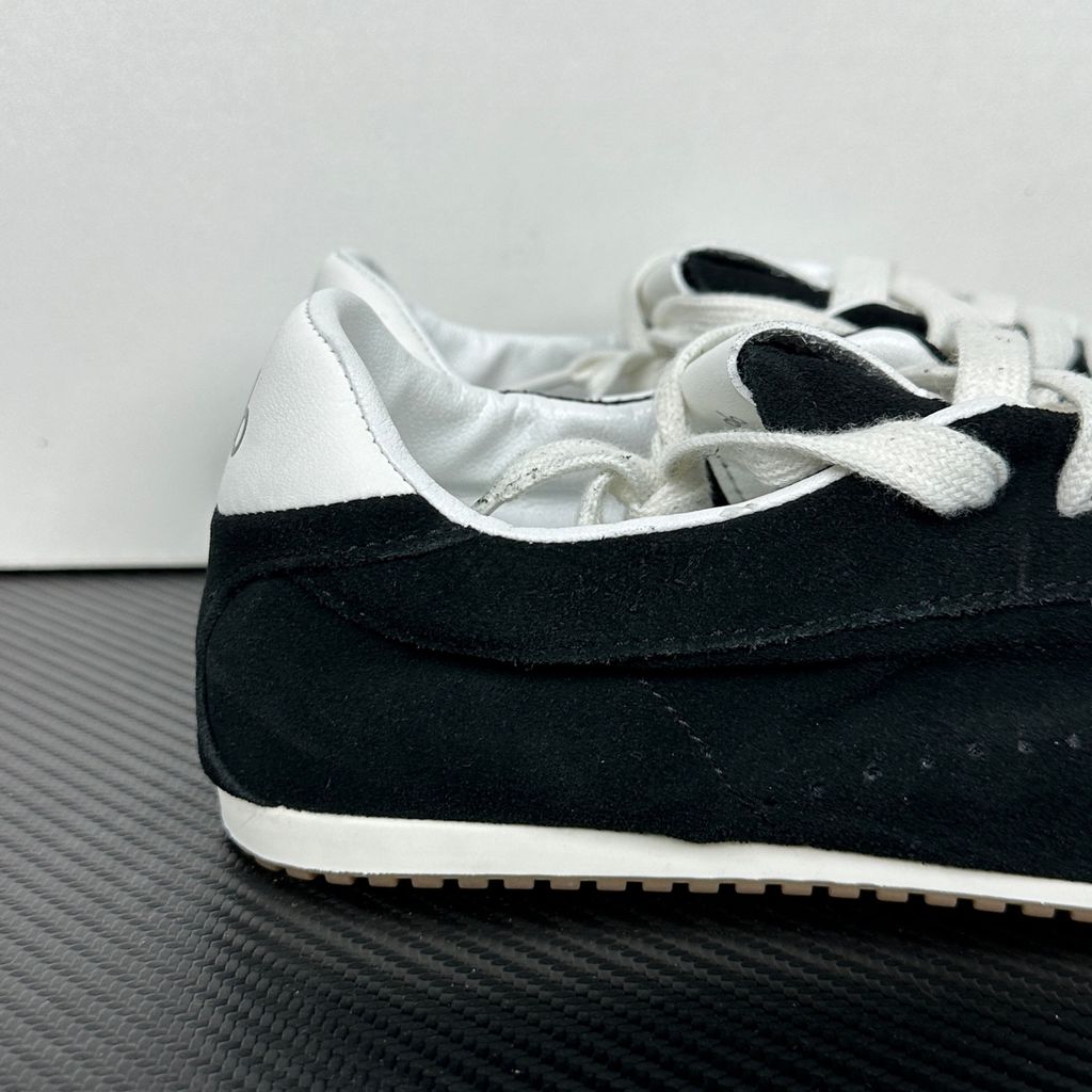The ALO Sunset Sneaker Black/Ivory (A0891U) is a low-profile lifestyle sneaker inspired by the polished street style of Sunset Boulevard. It combines a black suede upper, contrasting Ivory details, recovery-foam cushioning and a flat gum-rubber outsole.