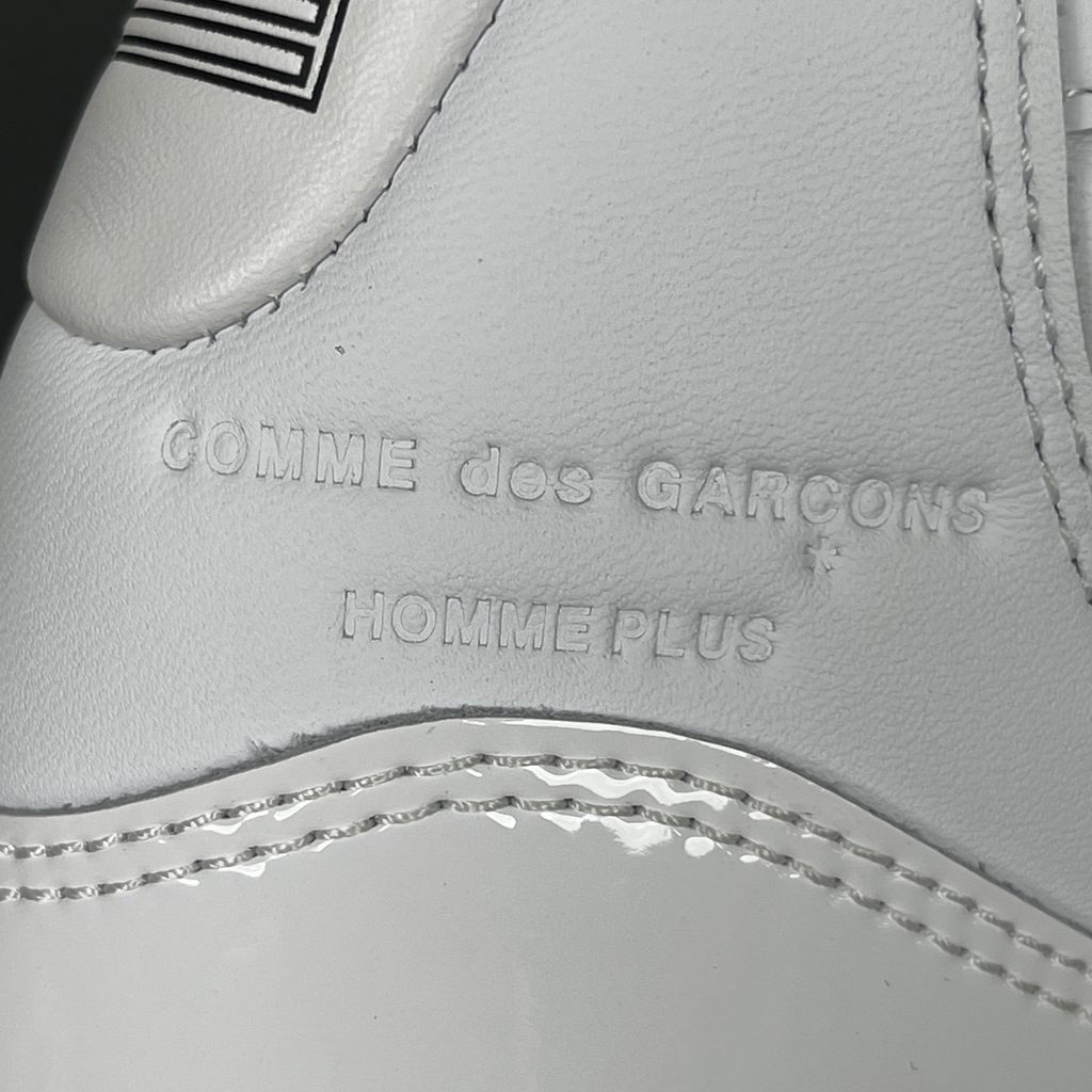 Jordan 11 Retro Comme des Garçons Homme Plus White IV7639-100 sneaker with a premium leather upper, tonal patent mudguard and CDG branding, side view.