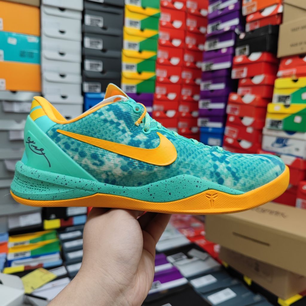 Side profile of the Nike Kobe 8 System 'Green Glow' basketball sneaker featuring a highly textured green reptile-scaled Engineered Mesh upper, a striking Laser Orange Nike Swoosh, Mineral Teal accents, and a low-profile cushioned midsole.