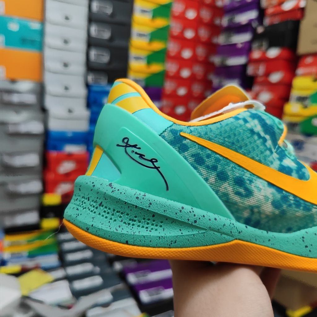 Side profile of the Nike Kobe 8 System 'Green Glow' basketball sneaker featuring a highly textured green reptile-scaled Engineered Mesh upper, a striking Laser Orange Nike Swoosh, Mineral Teal accents, and a low-profile cushioned midsole.