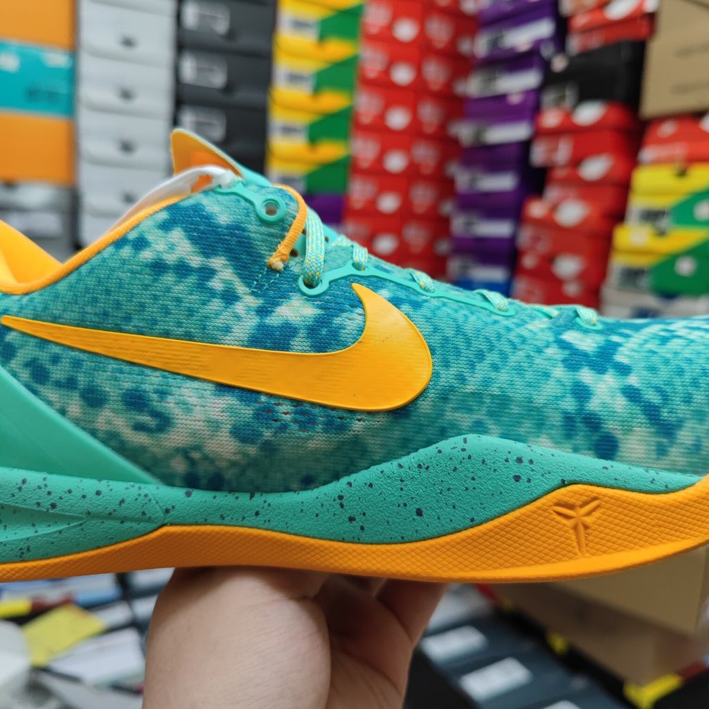 Side profile of the Nike Kobe 8 System 'Green Glow' basketball sneaker featuring a highly textured green reptile-scaled Engineered Mesh upper, a striking Laser Orange Nike Swoosh, Mineral Teal accents, and a low-profile cushioned midsole.