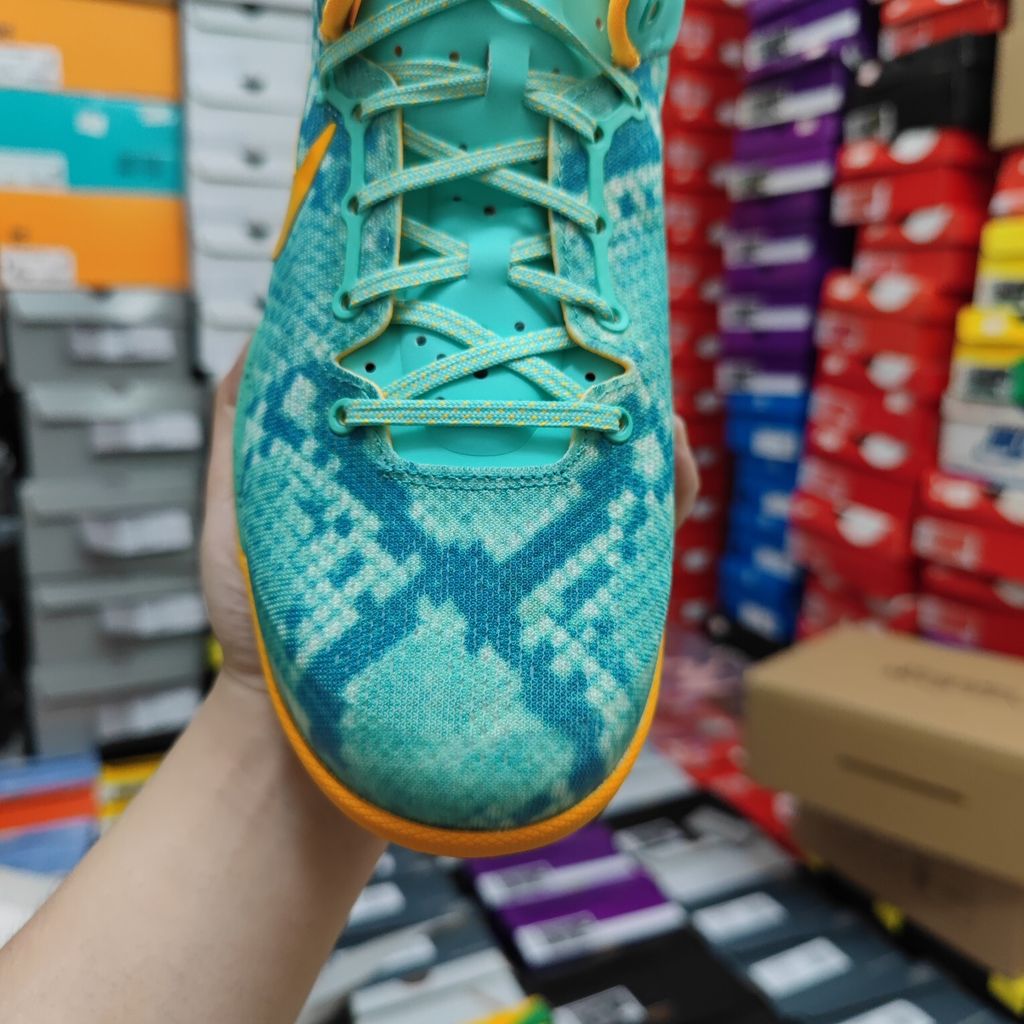 Side profile of the Nike Kobe 8 System 'Green Glow' basketball sneaker featuring a highly textured green reptile-scaled Engineered Mesh upper, a striking Laser Orange Nike Swoosh, Mineral Teal accents, and a low-profile cushioned midsole.