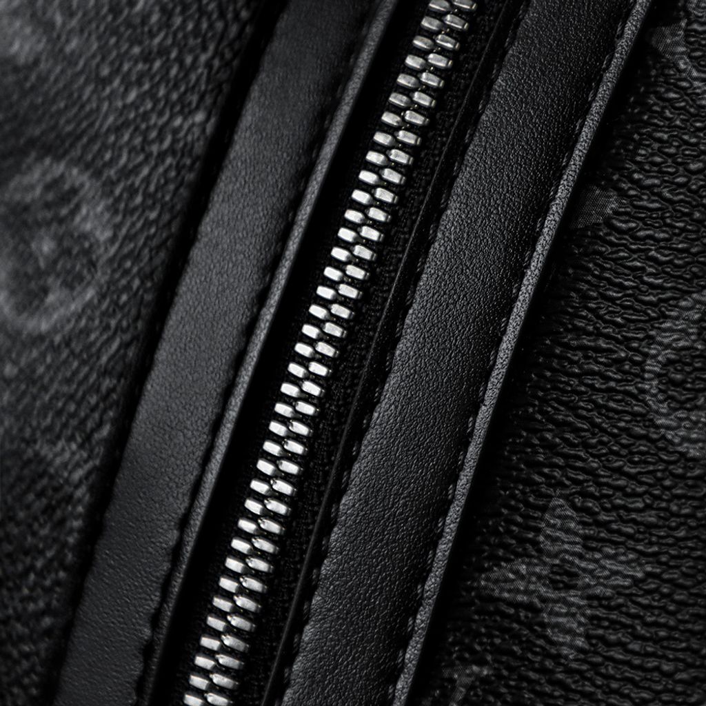 Front view of the authentic Louis Vuitton Discovery Backpack PM (image_b57668.jpg) featuring the iconic Monogram Eclipse grey and black coated canvas, a front zippered compartment, sleek black leather trim, and polished silver-tone hardware.