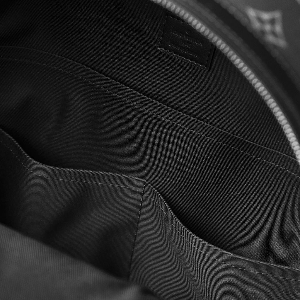 Front view of the authentic Louis Vuitton Discovery Backpack PM (image_b57668.jpg) featuring the iconic Monogram Eclipse grey and black coated canvas, a front zippered compartment, sleek black leather trim, and polished silver-tone hardware.