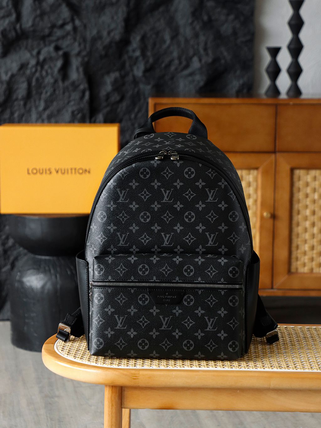 Front view of the authentic Louis Vuitton Discovery Backpack PM (image_b57668.jpg) featuring the iconic Monogram Eclipse grey and black coated canvas, a front zippered compartment, sleek black leather trim, and polished silver-tone hardware.