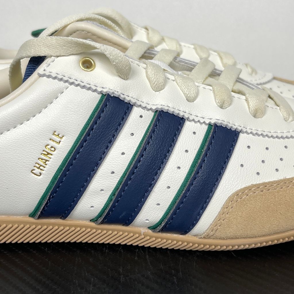 Shop adidas Chang Le LA1355 in Core White and Warm Sandstone with perforated tumbled leather, double-stitched T-toe detailing and a low-profile retro silhouette.