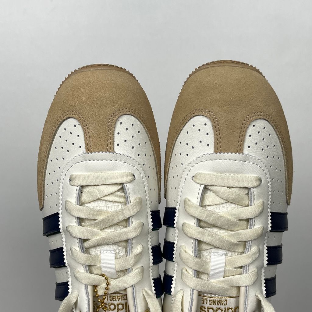 Shop adidas Chang Le LA1355 in Core White and Warm Sandstone with perforated tumbled leather, double-stitched T-toe detailing and a low-profile retro silhouette.