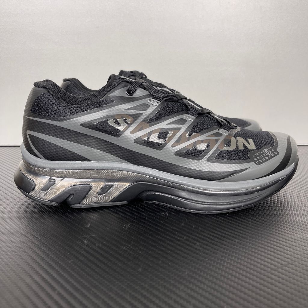 Shop MM6 Maison Margiela x Salomon XT-MM6 L49200300 in Black and Grey with technical mesh, layered synthetic overlays, MM6 graphics and a sculpted rubber sole.