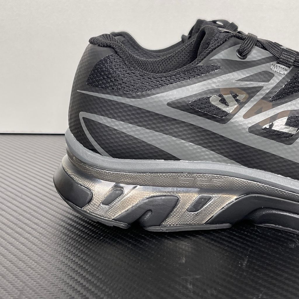 Shop MM6 Maison Margiela x Salomon XT-MM6 L49200300 in Black and Grey with technical mesh, layered synthetic overlays, MM6 graphics and a sculpted rubber sole.