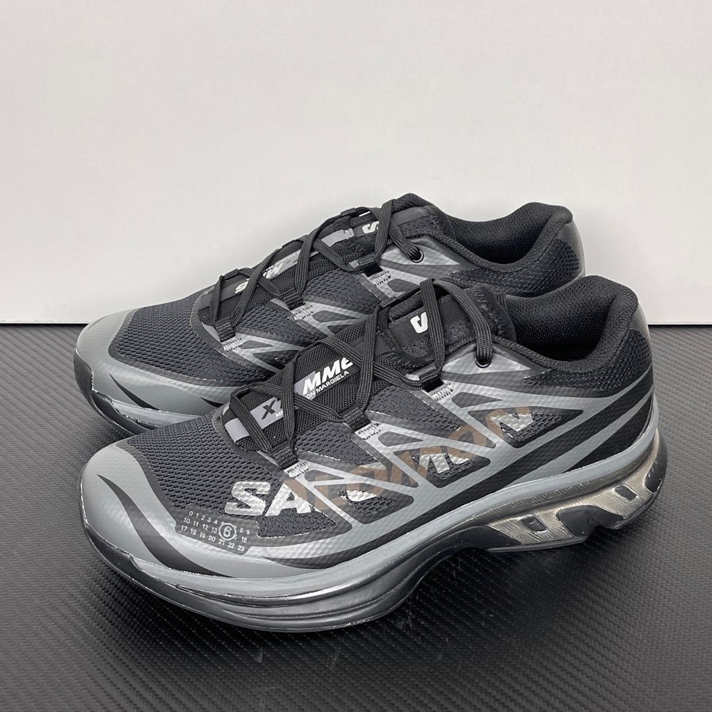 Shop MM6 Maison Margiela x Salomon XT-MM6 L49200300 in Black and Grey with technical mesh, layered synthetic overlays, MM6 graphics and a sculpted rubber sole.