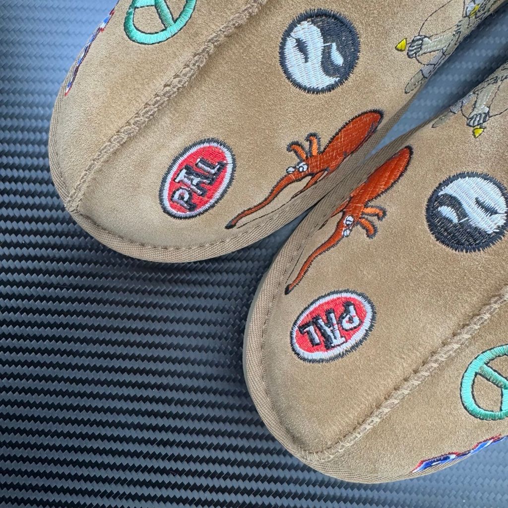 Shop UGG x Palace Tasman Slipper 1157290-CHE in Chestnut suede with embroidered Palace graphics, braided collar, plush lining, EVA midsole and Treadlite outsole.