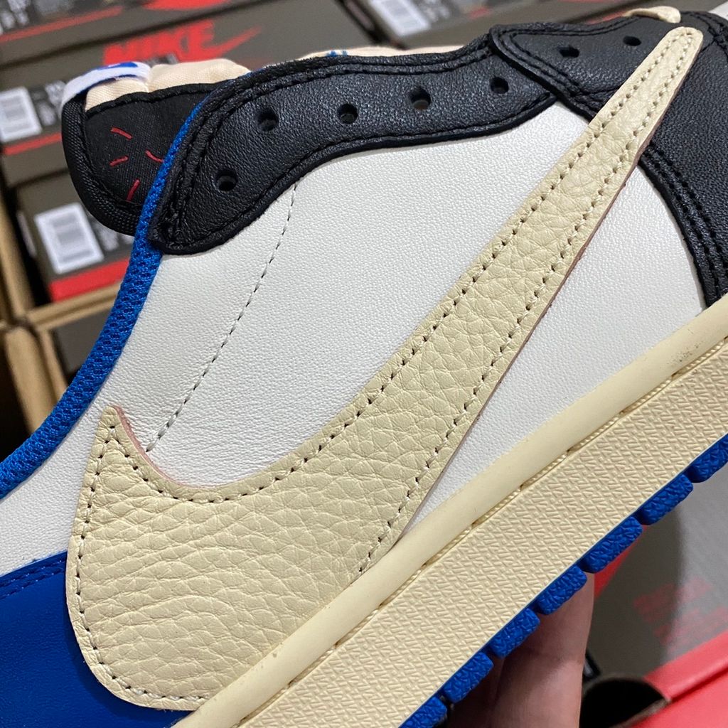 Shop Fragment Design x Travis Scott x Air Jordan 1 Low OG SP DM7866-140 in White, Black, Royal and Sail with reverse Swoosh and collaborative heel branding.