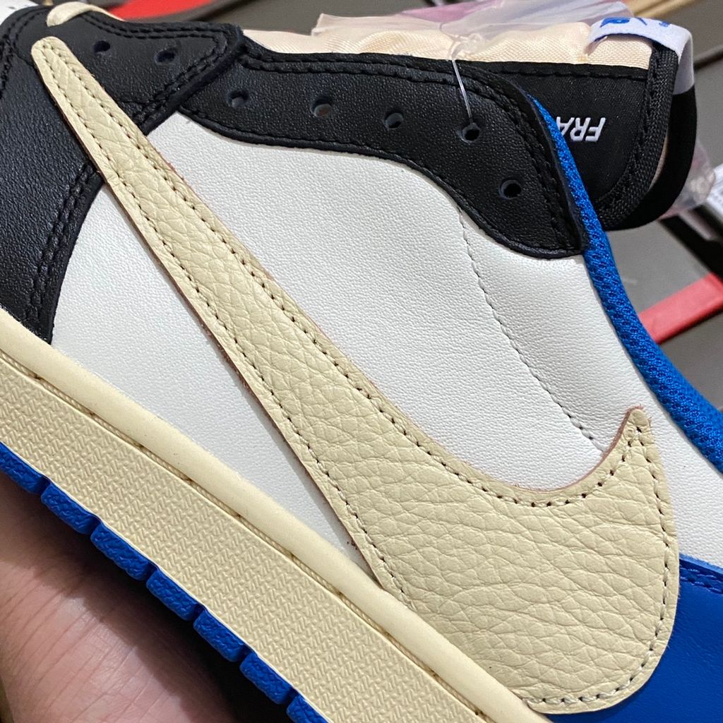 Shop Fragment Design x Travis Scott x Air Jordan 1 Low OG SP DM7866-140 in White, Black, Royal and Sail with reverse Swoosh and collaborative heel branding.