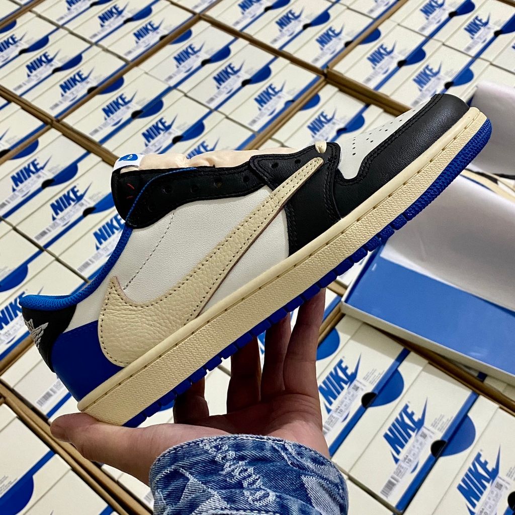 Shop Fragment Design x Travis Scott x Air Jordan 1 Low OG SP DM7866-140 in White, Black, Royal and Sail with reverse Swoosh and collaborative heel branding.