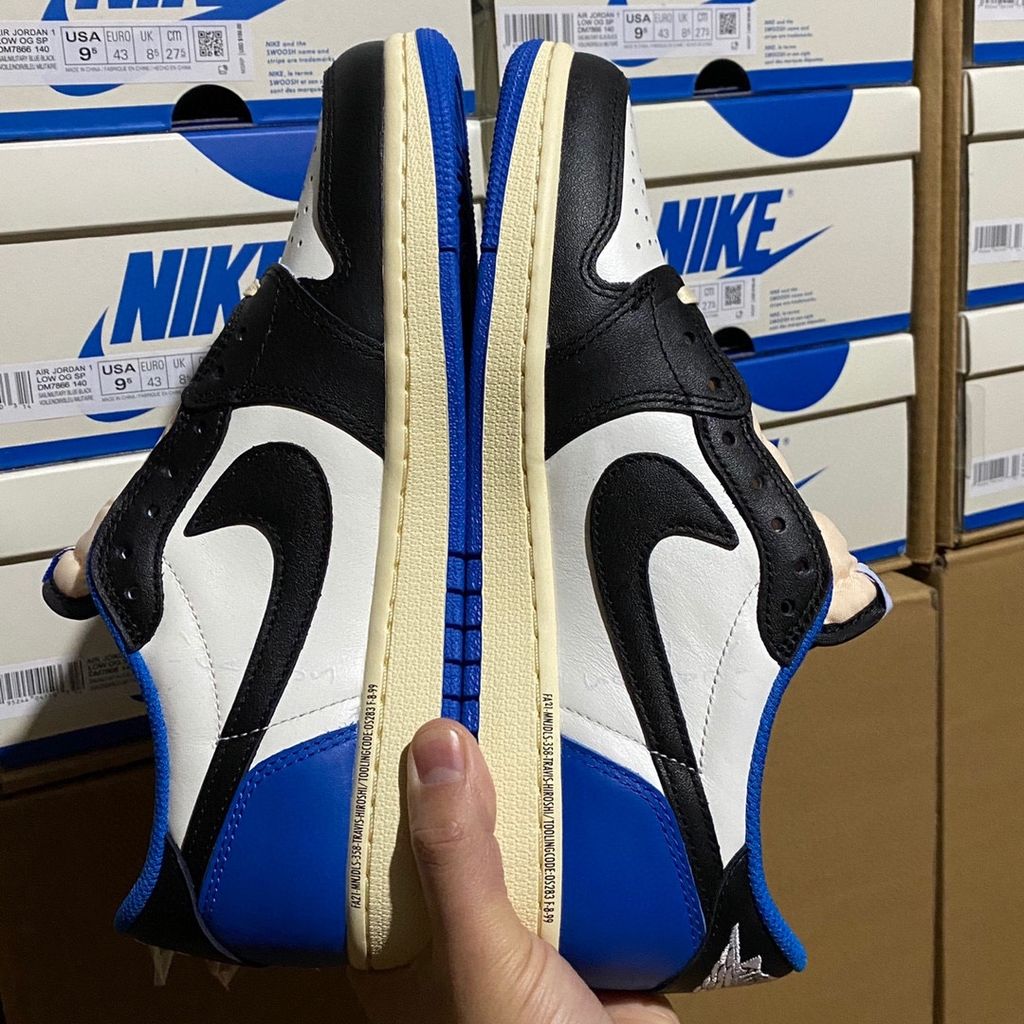 Shop Fragment Design x Travis Scott x Air Jordan 1 Low OG SP DM7866-140 in White, Black, Royal and Sail with reverse Swoosh and collaborative heel branding.